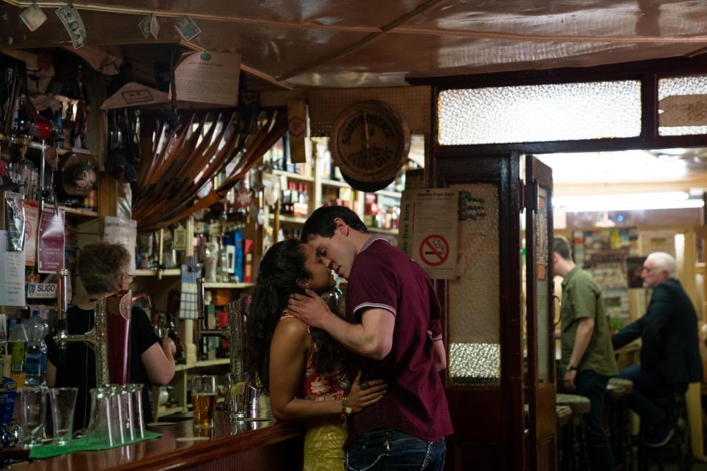 A scene from "Sex Education" with two young actors kissing at a bar.