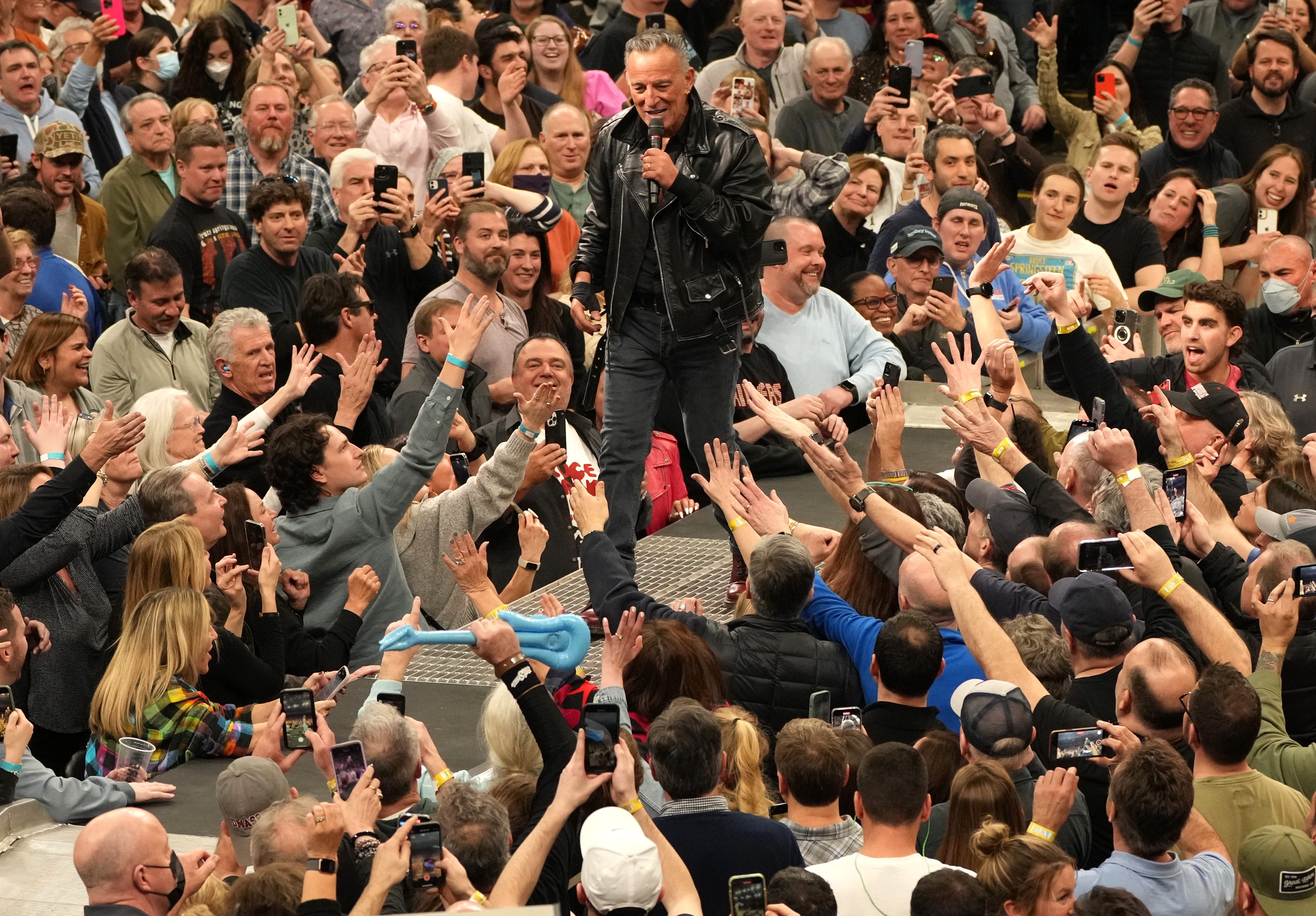 Fans surround Bruce Springsteen at a concert as he performs live on stage. 