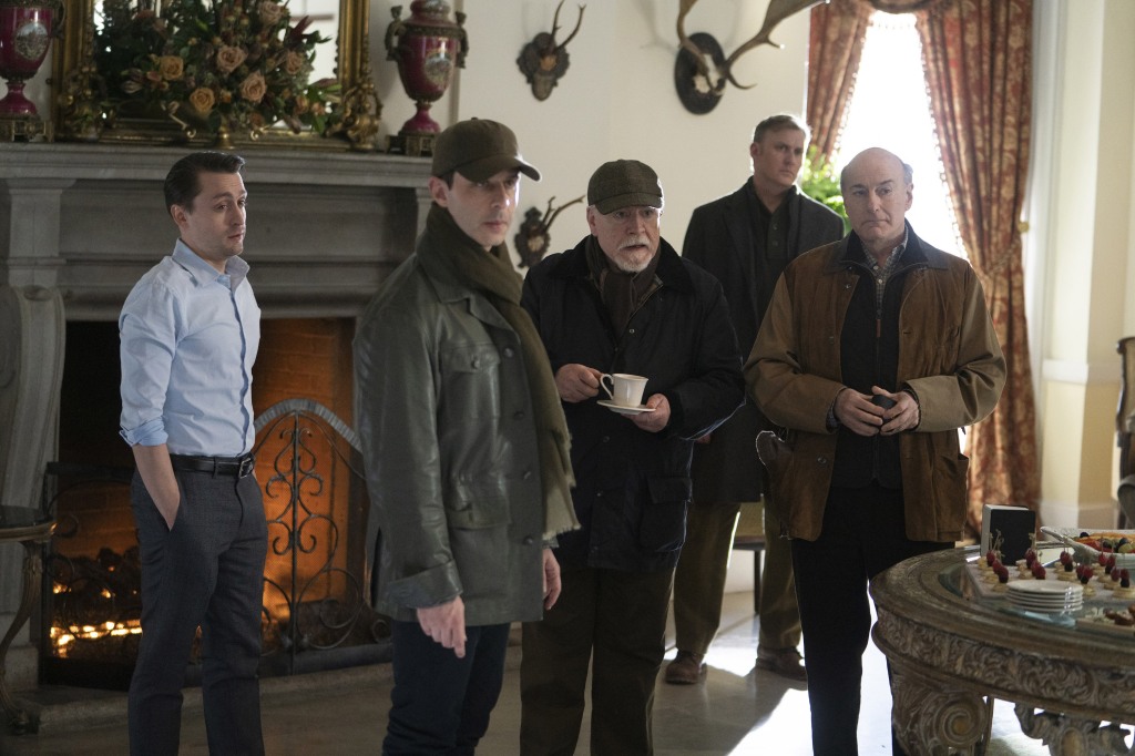 Kieran Culkin, Jeremy Strong, Brian Cox, Peter Friedman in "Succession" standing in a line together in  a room. 