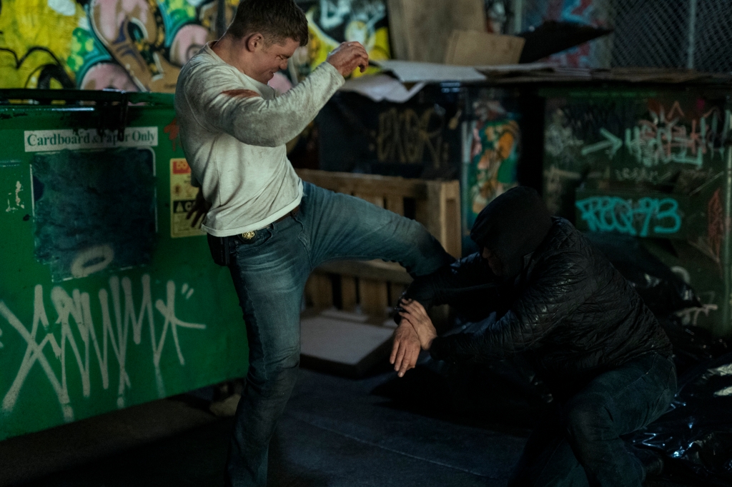Gabriel Basso fighting next to a dumpster. 