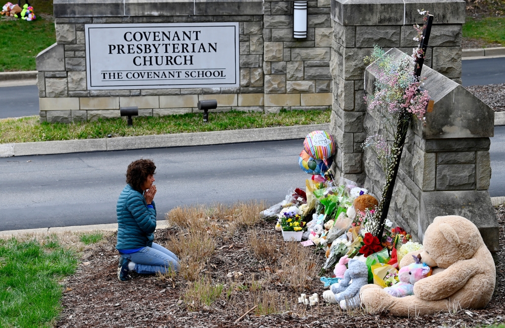 Robin Wolfeden prays in front of a makeshift memorial at the entrance to The Covenant School.