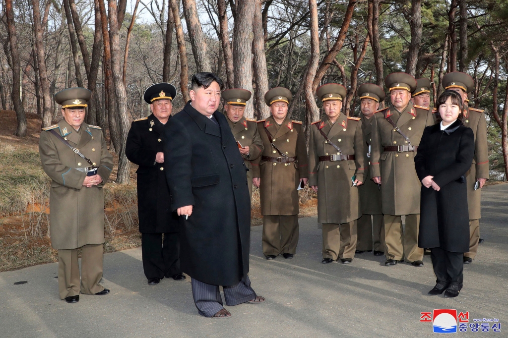 Kim Jong Un stands with military officials at an unknown location for a military exercise. 