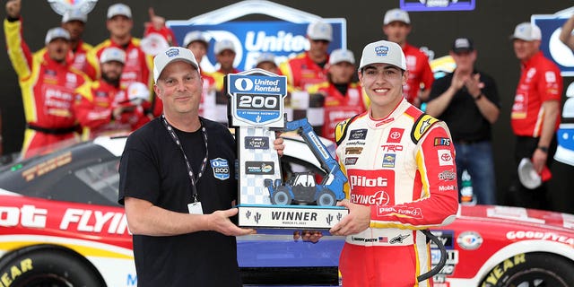 Sammy Smith, driver of the #18 Pilot Flying J Toyota, is presented the United Rentals 200 trophy in victory lane after winning the NASCAR Xfinity Series United Rentals 200 at Phoenix Raceway on March 11, 2023 in Avondale, Arizona.