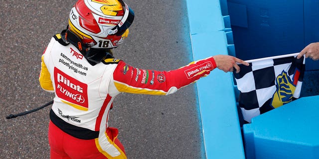 Sammy Smith, driver of the #18 Pilot Flying J Toyota, receives the checkered flag after winning the NASCAR Xfinity Series United Rentals 200 at Phoenix Raceway on March 11, 2023 in Avondale, Arizona.