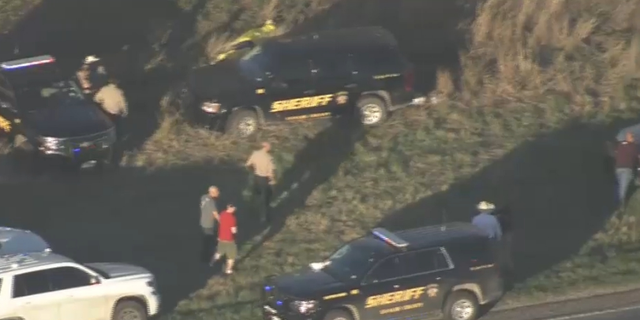 Law enforcement vehicles and officers photographed via helicopter investigating train cars where more than a dozen migrants were found suffocating near San Antonio, TX. (Credit: KENS 5 San Antonio)