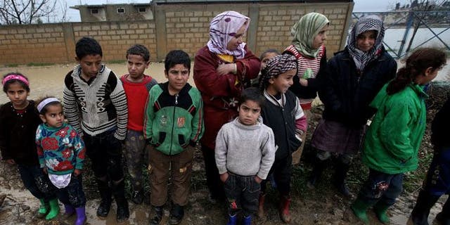 Syrian refugees pose for a photograph after their tents flooded from the rain at a temporary refugee camp in the eastern Lebanese town of Al-Faour near the border with Syria.