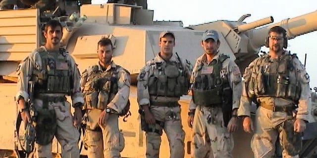 The team in front of a tank at Objective Grizzley, later FOB Grizzley, outside Tikrit, Iraq, April 12, 2003. Operators had taken control of a former Iraqi Army base. Tanks were flown into our area via the H1 Airfield to provide security for their new staging base and to provide fire support as they prepared to enter Tikrit. Pictured from left to right, Brad Thomas, Craig Palmer, Chris VanSant, Mike Hefner and Shawn Stevens.