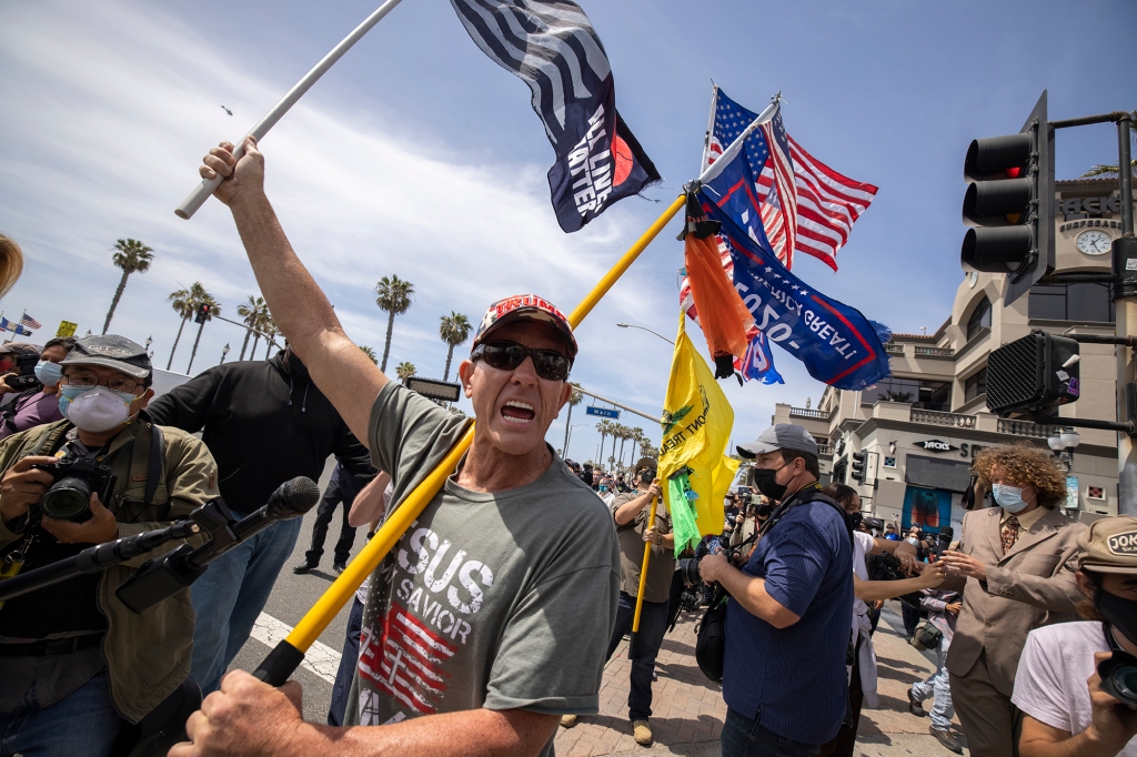 Trump supporter carries flags at the site of a "White Lives Matter" rally on April 11, 2021 in Huntington Beach, California.