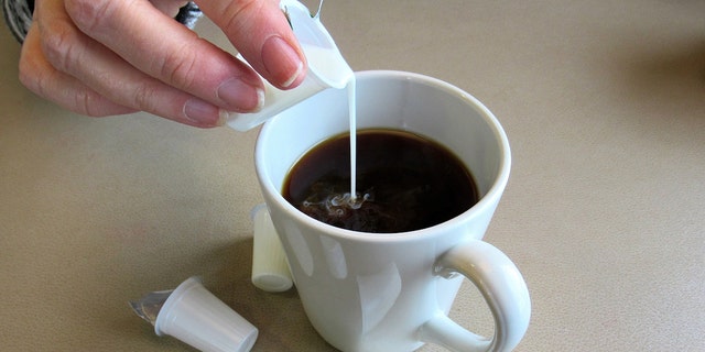 People tend to drink coffee with milk, sugar and possibly a snack — all of which could cause weight gain, one doctor noted. Here, a person adds half-and-half to a cup of coffee. 