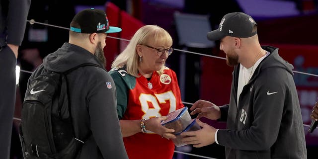 Mother Donna Kelce (C) gives cookies to her son's Jason Kelce (L) #62 of the Philadelphia Eagles and Travis Kelce (R) #87 of the Kansas City Chiefs during Super Bowl LVII Opening Night presented by Fast Twitch at Footprint Center on February 06, 2023, in Phoenix, Arizona.