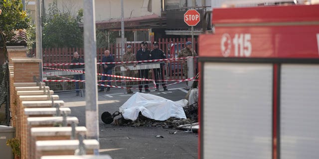 The burned remains of one of the two Italian Air Force U-208 aircrafts that crashed in Guidonia, on the outskirts of Rome, Tuesday, March 7, 2023, is covered with a white cloth in the residential district where it fell. Two pilots died in the crash.