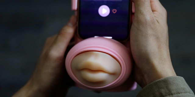 Jing Zhiyuan uses a remote kissing device "Long Lost Touch," as he demonstrates how to use it during an interview with Reuters, at his home in Beijing March 12, 2023.