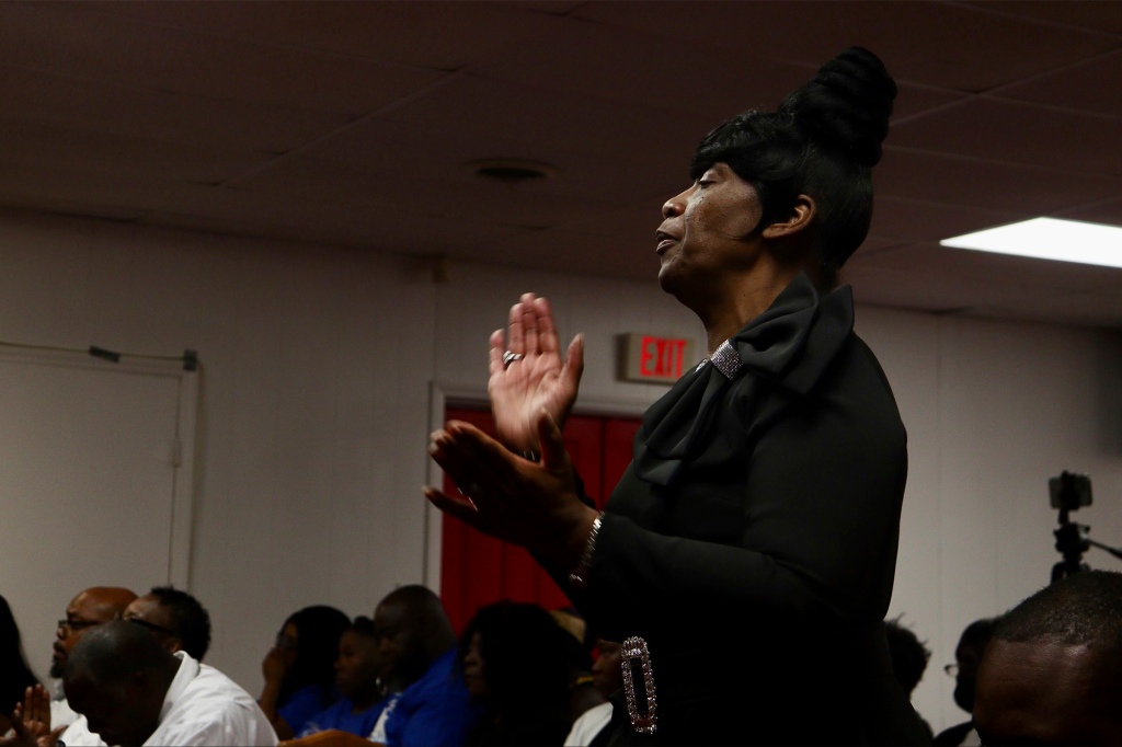 An attendee claps during a song at the funeral for Shaeed Woodard.