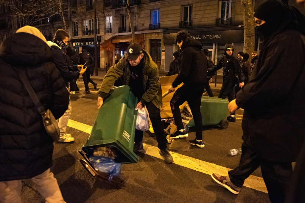 A protester empties a rubbish bin in a Parisian street during protests and riots in Paris, France on March 22, 2023. 