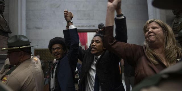 Reps. Justin Pearson, Justin Jones and Gloria Johnson hold their hands up as they exit the House Chamber doors at the state Capitol in Nashville, Tennessee on April 3, 2023.