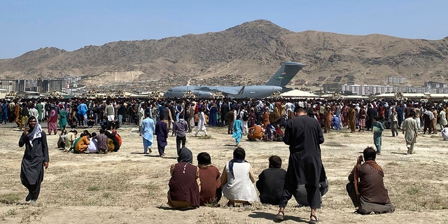 Hundreds of people gather near a U.S. Air Force C-17 transport plane at the perimeter of the international airport in Kabul, Afghanistan, Aug. 16, 2021.