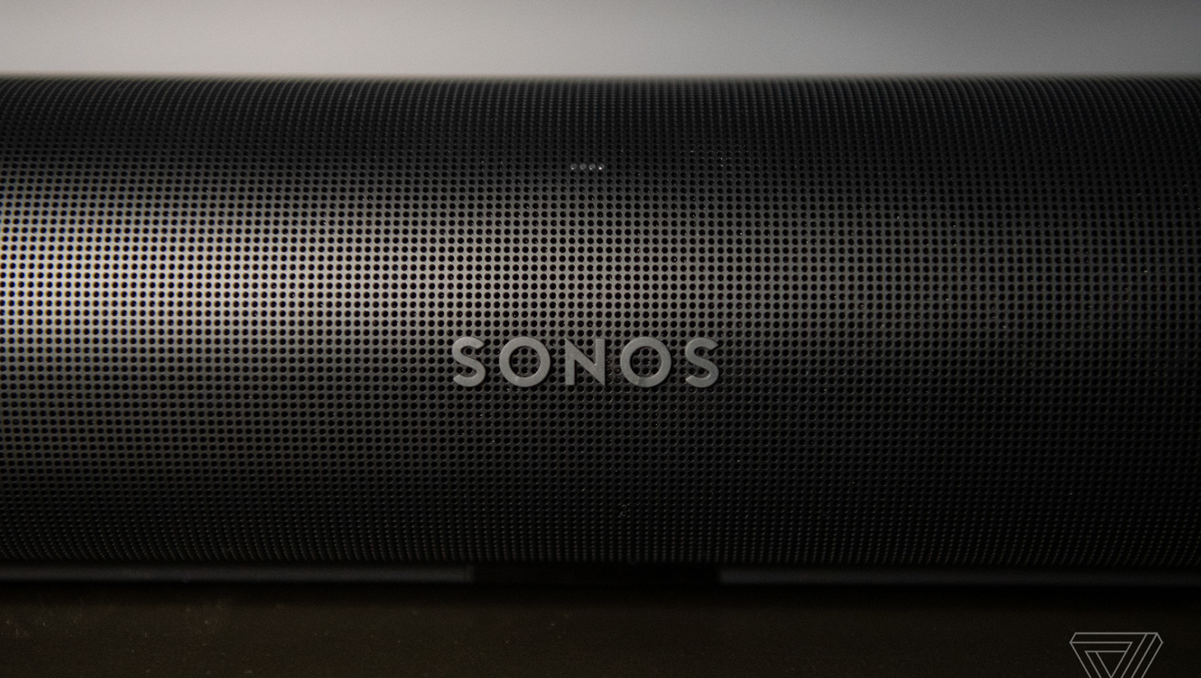 A detail shot of the front of the Sonos Arc, showing the Sonos logo and many perforated holes in the outer casing.