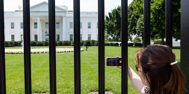 Tourists visit the fence line on the north side of the White House