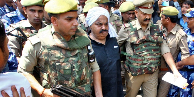 Police officers escort Atiq Ahmed, a former lawmaker accused in several criminal cases, outside a court in Prayagraj, India, April 13, 2023. (Reuters/Ritesh Shukla)