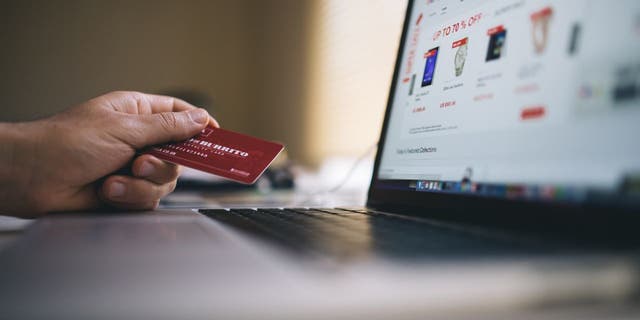 Person holds credit card as they buy items online