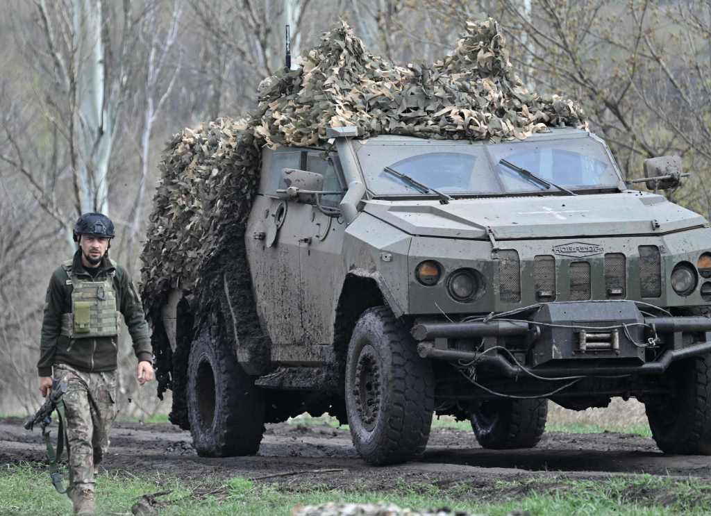 An armoured vehicle rolls past a Ukrainian serviceman on a road near the town of Bakhmut, Donetsk region on April 8, 2023. 