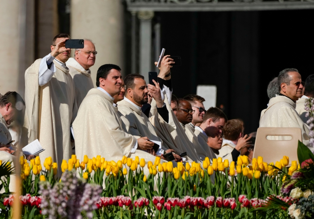 Priests take pictures in St. Peter's Square at The Vatican where Pope Francis will celebrate the Easter Sunday mass on April 9, 2023. 