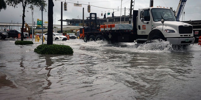 Exit 2 off of the MacArthur Causeway floods over the road and onto the sidewalk during a rainstorm, Wednesday, April 12, 2023, in Miami. 