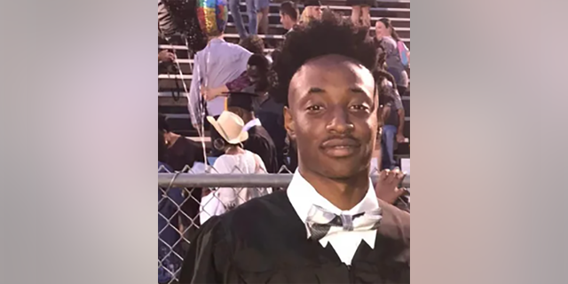 Corbin Dahmontrey Holston seen in high school graduation gown with diploma