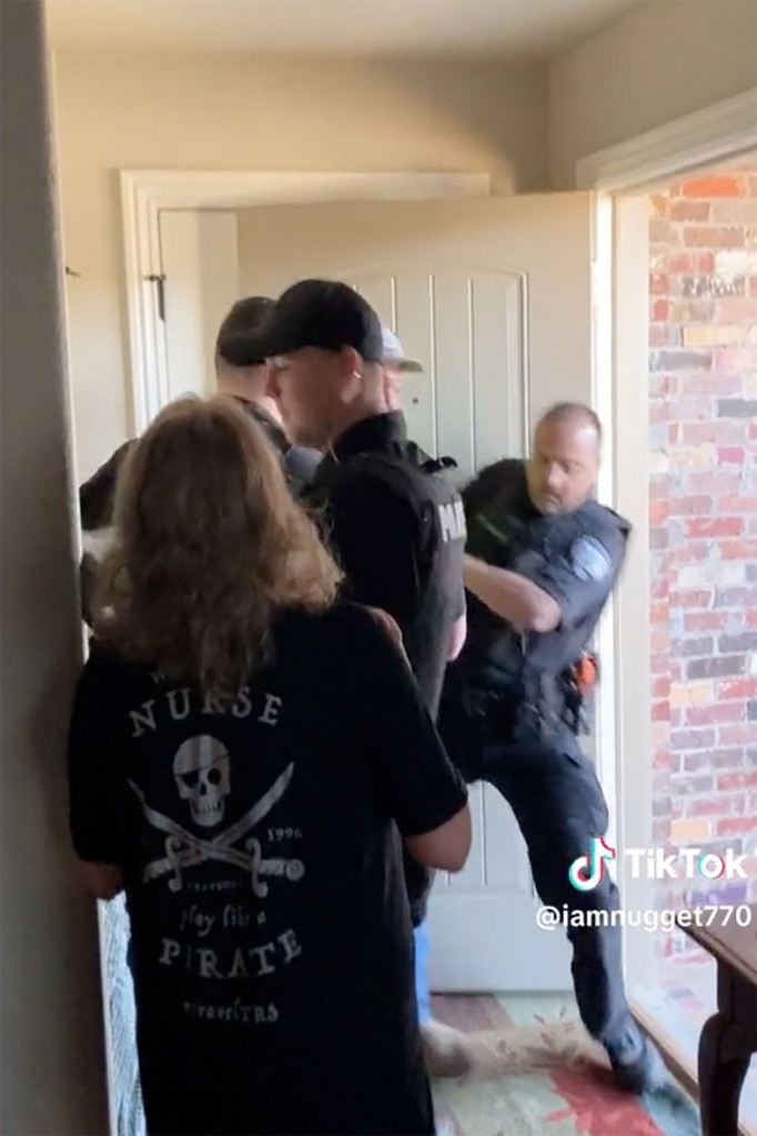 After a brief struggle, officers are forced to shove the father out the door of his own house.