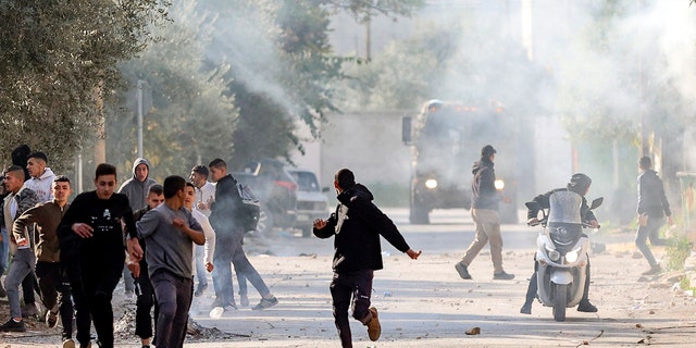 Palestinians run for cover during confrontations with Israeli forces in the occupied-West Bank city of Jenin, on January 26, 2023. 