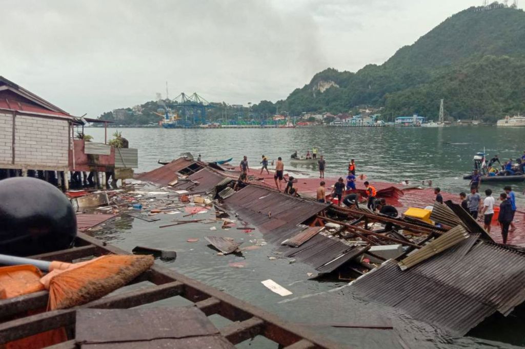 People stand on the roofing of collapsed shops in the port after a 5.1-magnitude earthquake in Jayapura, Indonesia's eastern province of Papua.