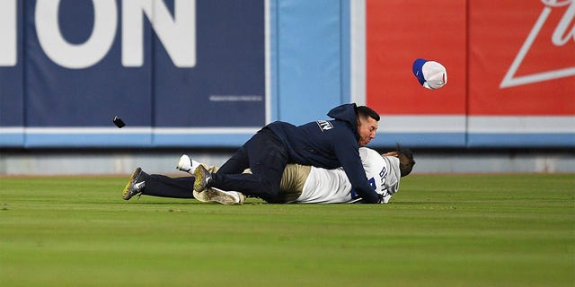 A Dodger fan is tackled by security as he tries to propose to his girlfriend in the stands during the MLB game between the Arizona Diamondbacks and the Los Angeles Dodgers on March 30, 2022, at Dodger Stadium in Los Angeles, CA. 