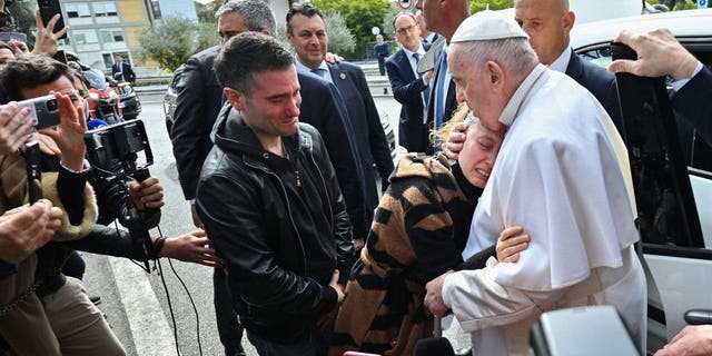 Pope Francis hugs Serena Subania as her husband Matteo Rugghia (L) reacts, a couple who lost their five-year-old child a day earlier, as the Pope leaves the Gemelli hospital on April 1, 2023 in Rome, after being discharged following treatment for bronchitis.