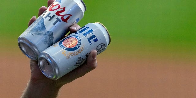 A vendor holds Coors Light and Miller Lite cans during a game between the Toronto Blue Jays and Brewers at American Family Field on June 24, 2022, in Milwaukee.