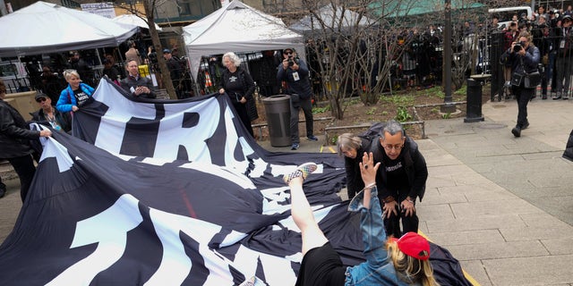 The Trump supporter is confronted by anti-Trump protesters while laying on the ground.