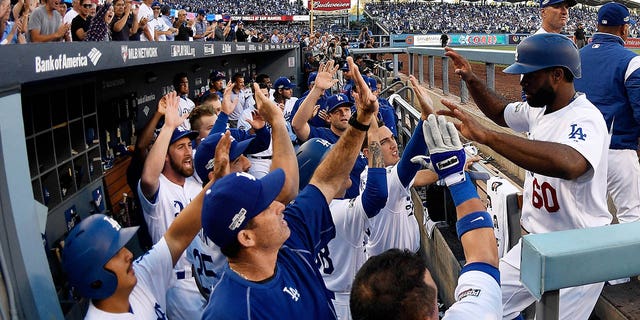 Andrew Toles (60) of the Los Angeles Dodgers celebrates with teammates in the eighth inning after scoring during Game 4 of the National League Division Series against the Washington Nationals at Dodger Stadium Oct. 11, 2016, in Los Angeles.  