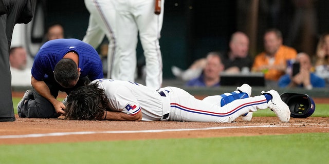 Apr 3, 2023; Arlington, Texas, USA; Texas Rangers left fielder Josh Smith (47) hits the ground after getting hit by a pitch thrown by Baltimore Orioles relief pitcher Danny Coulombe (not shown) during the third inning at Globe Life Field.