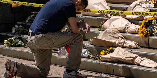 Bryan Menefee kneels in front of the memorial set up at Old National Bank in downtown Louisville, Kentucky, on April 11, 2023.