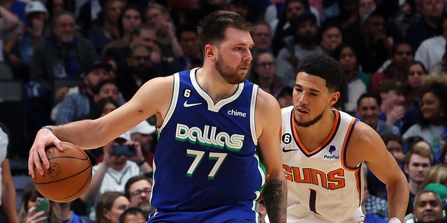 Luka Doncic #77 of the Dallas Mavericks is guarded by Devin Booker #1 of the Phoenix Suns in the second half at American Airlines Center on December 05, 2022 in Dallas, Texas. 