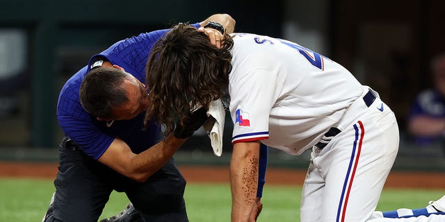 Matt Lucero, athletic trainer for the Texas Rangers, attends to Josh Smith #47 after he was hit in the face by a pitch in the third inning against the Baltimore Orioles at Globe Life Field on April 03, 2023 in Arlington, Texas.