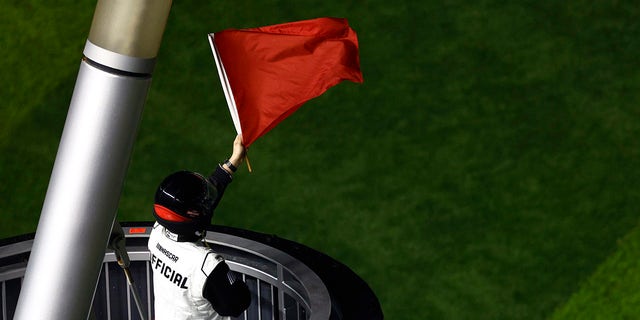 A NASCAR official waves the red flag.