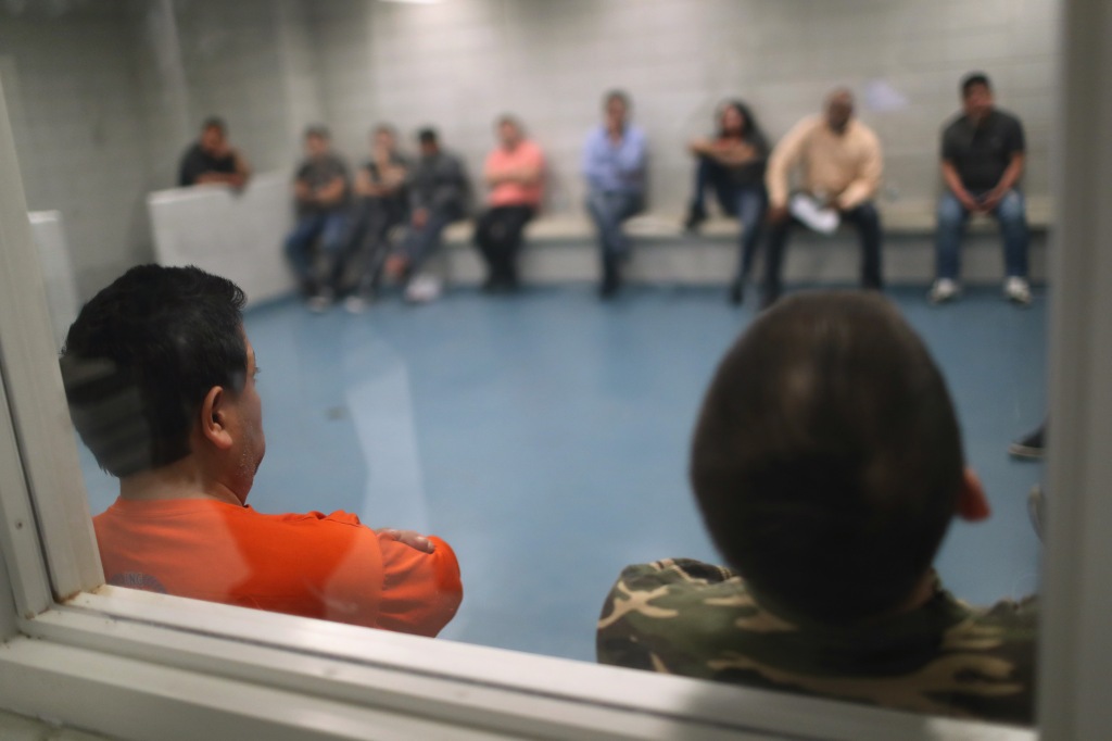 Undocumented immigrants wait in an Immigration and Customs Enforcement (ICE), processing center after they were arrested.