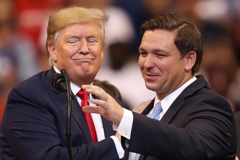 President Donald Trump pats Gov. Ron DeSantis on the shoulder at a 2019 campaign rally. 