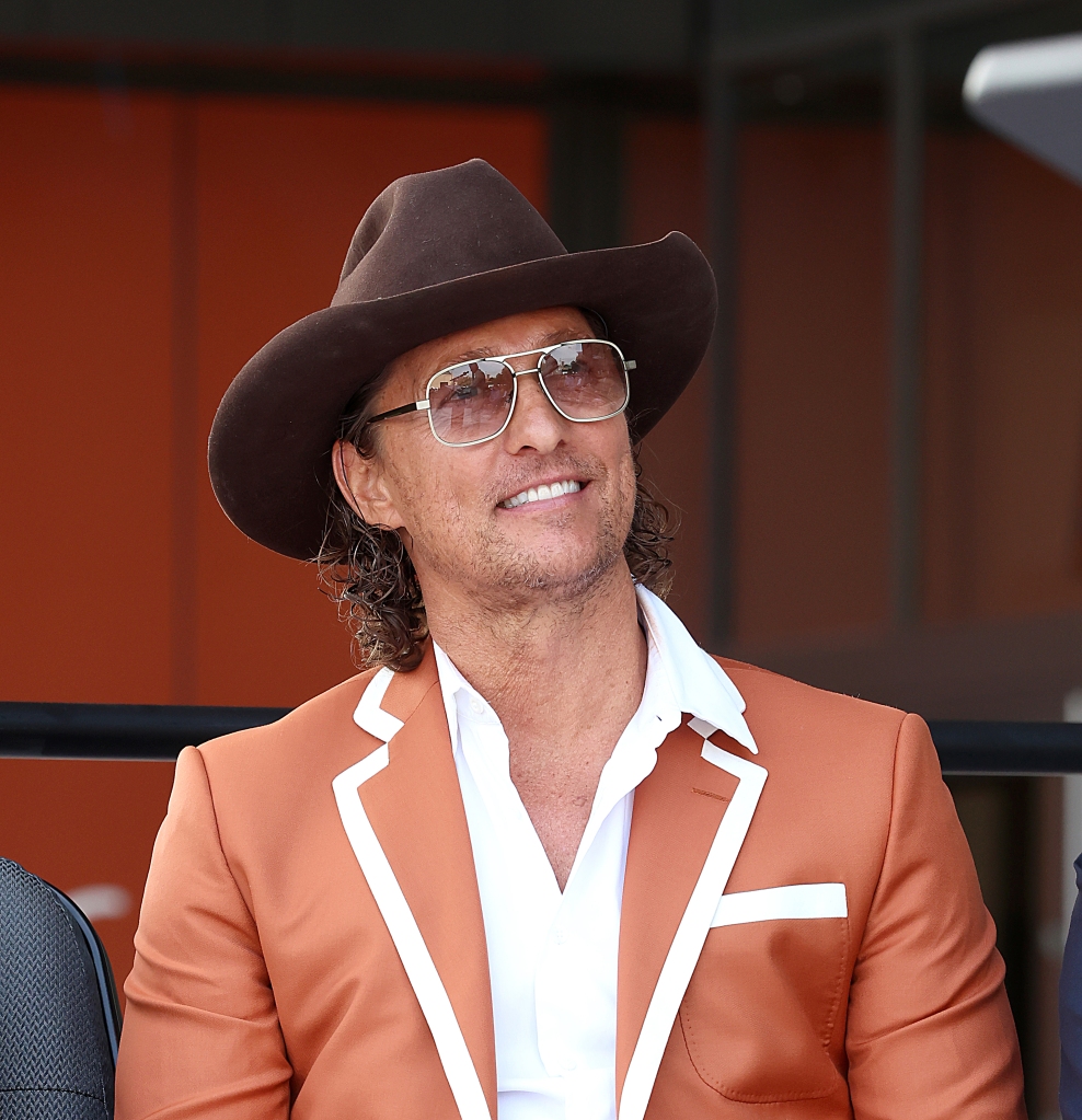 Matthew McConaughey smiling wearing a cowboy hat and sunglasses. 