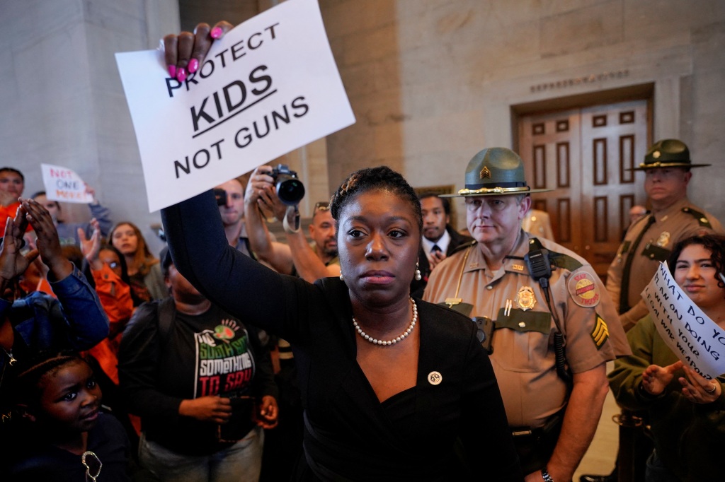 State Senator Charlane Oliver holding sign saying: "Protect kids not guns."