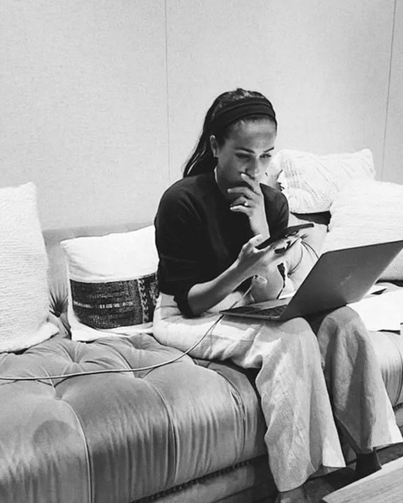 Meghan Markle, who only worked one hour a week on her Archewell foundation, sits on couch working on her laptop. 
