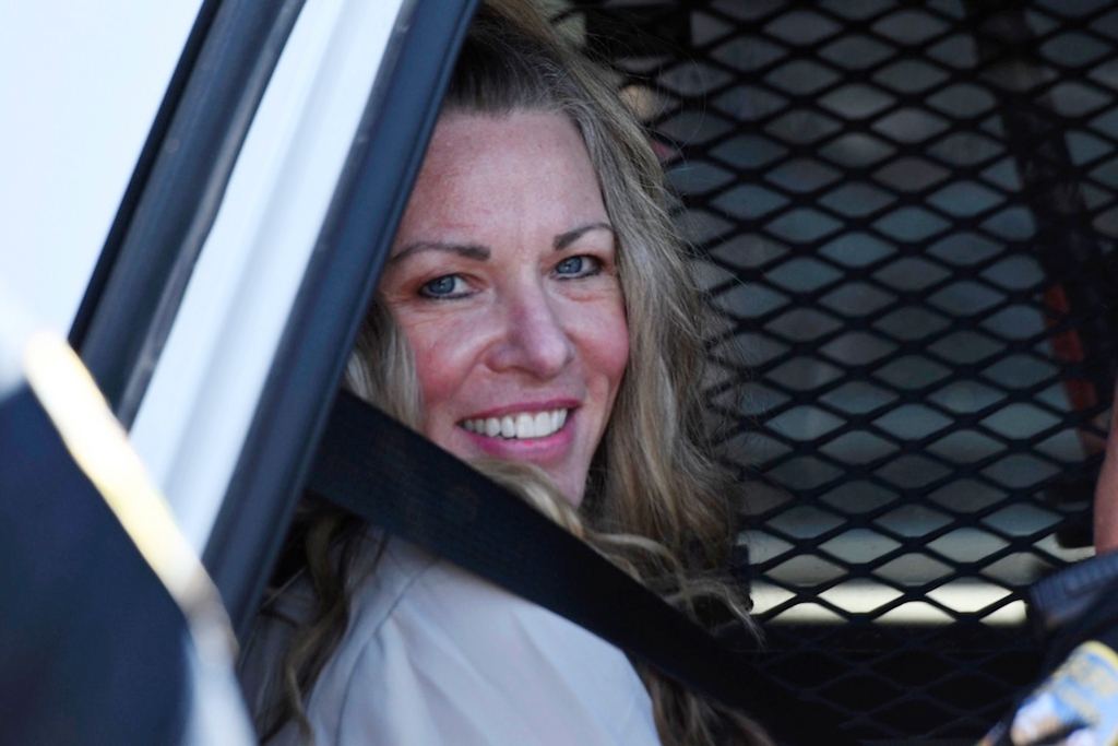 Lori Vallow Daybell smiling in the back of a police car
