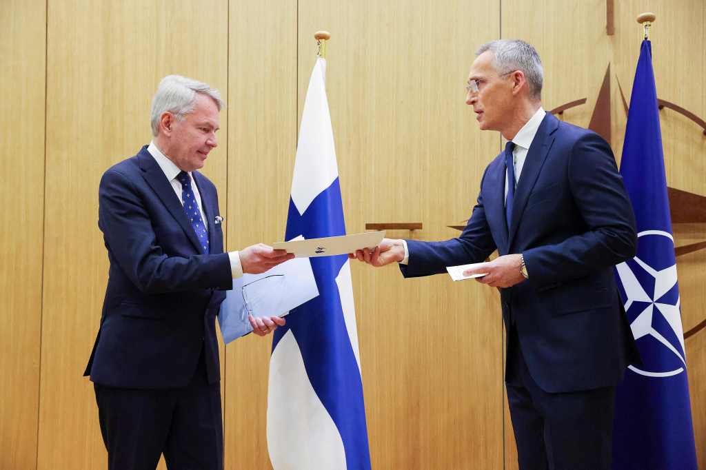 NATO Secretary-General Jens Stoltenberg (R) hands over Finland's accesssion documents to NATO to Finnish Foreign Affairs Minister Pekka Haavisto, 