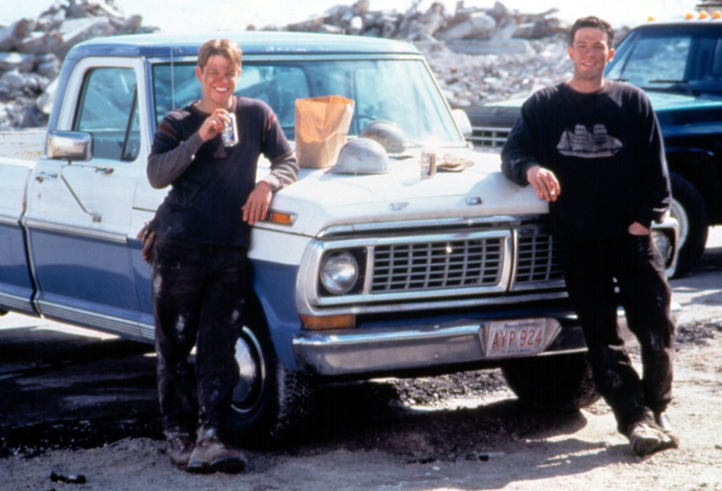 Matt Damon and Ben Affleck in 1997 in "Good Will Hunting" smiling standing next to a car with dirt on their faces. 