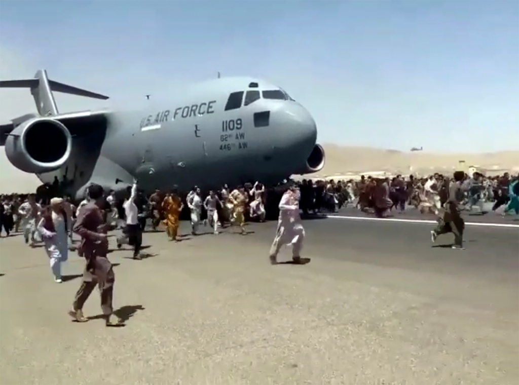 Hundreds of people run alongside a U.S. Air Force C-17 transport plane